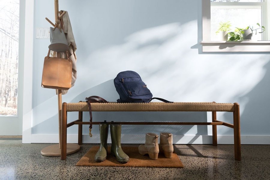 A hallway vignette featuring a bench, hat stand, bags and boots.  The walls are painted in Beacon Gray 2128-60 and the woodwork features Gray Owl 2138-60.