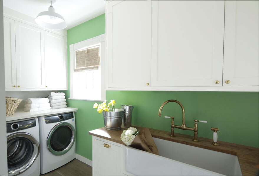 A laundry room with Super White OC-152 cabinets and woodwork paired with Cedar Green 2034-40 on the walls.