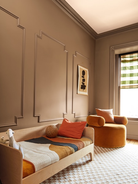 A child's bedroom with panelled walls painted in Chowning's Tan CW-195 and a ceiling painted in Tissue Pink 1163. The space is styled with autumnal colour accessories.