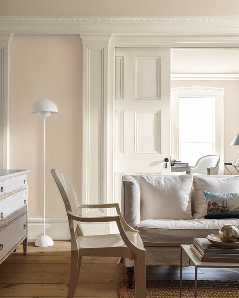 A sitting room with walls painted in First Crush CSP-310, showcasing sliding panels doors and decorative mouldings painted in Swiss Coffee OC-45.